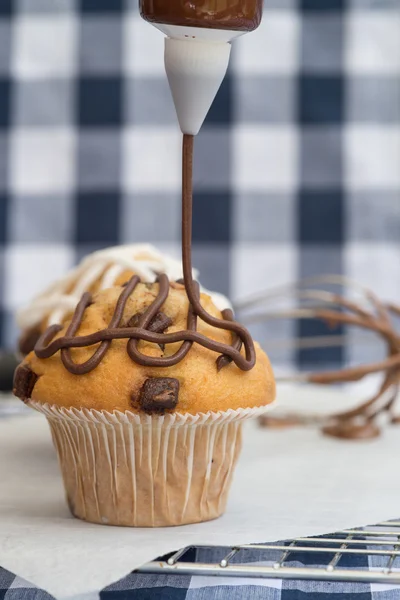 Icing frosting being put onto home made chocolate chip muffins — Stock Photo, Image