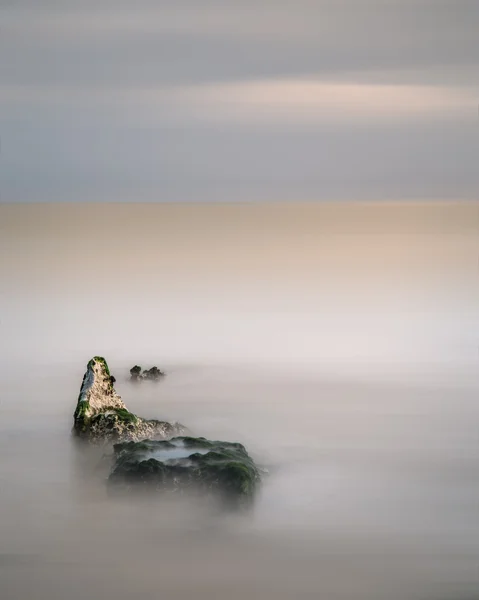 Stunning minimal long exposure landscape of rocks in ocean — Stock Photo, Image