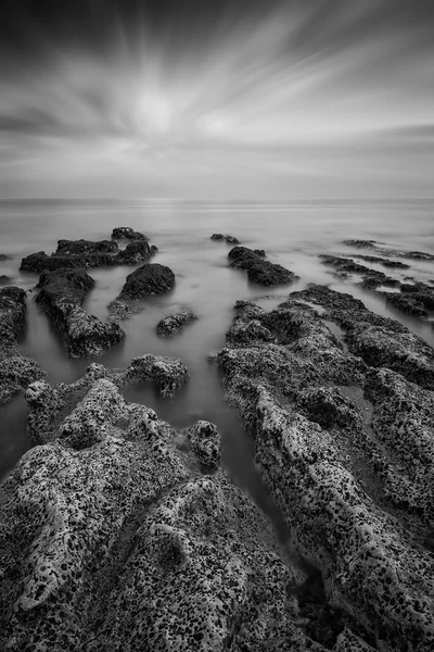 Paesaggio bianco e nero con vista sul mare con riva rocciosa e — Foto Stock