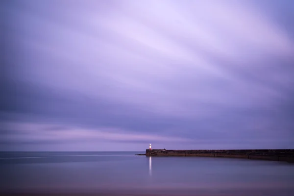 Stunning long exposure landscape lighthouse at sunset with calm — Stock Photo, Image