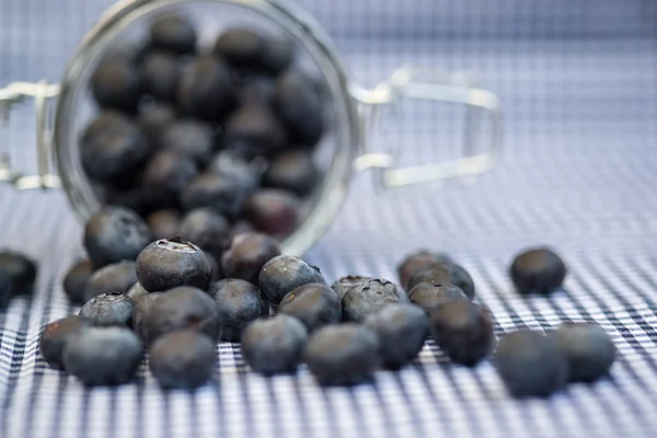 Fresh blueberries falling out of glass jar — Stock Photo, Image
