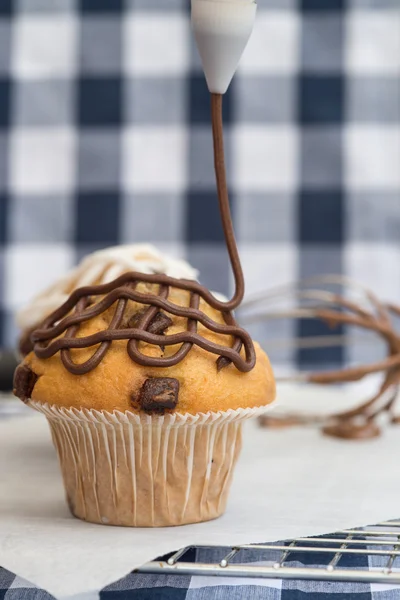 Icing frosting being put onto home made chocolate chip muffins — Stock Photo, Image