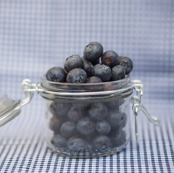 Fresh blueberries falling out of glass jar — Stock Photo, Image
