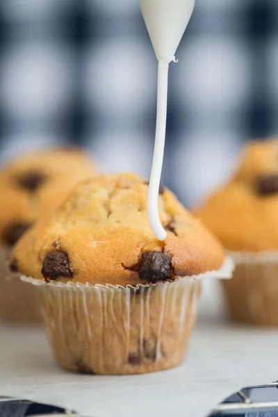 Icing frosting being put onto home made chocolate chip muffins — Stock Photo, Image