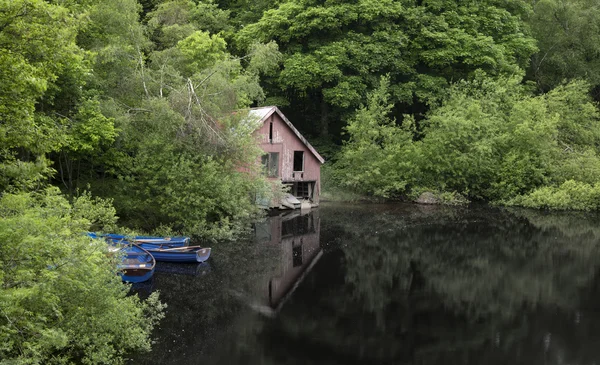 Derelict old retro boathouse and rowing boats hidden in forest l — Stock Photo, Image