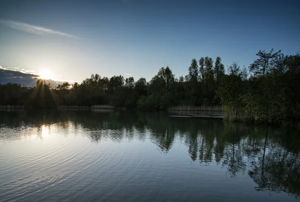 Sommer pulsierender Sonnenuntergang, der sich im ruhigen Wasser des Sees widerspiegelt — Stockfoto