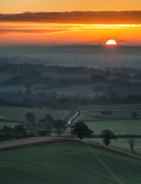 Impressionante nascer do sol sobre camadas de nevoeiro na paisagem rural — Fotografia de Stock