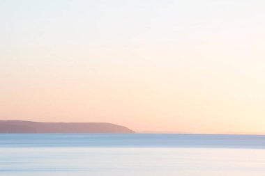 Cornwall 'daki Pentewan Kumları' nın üzerinde çarpıcı bir gün doğumu canlı gökyüzü ve uzun pozlu okyanusla