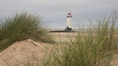Talacre sahilindeki deniz fenerinin güzel gündoğumu görüntüsü dramatik bir gökyüzü ve seçici odaklı bulutlarla birlikte.