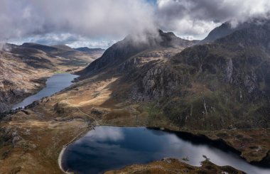 Uçan İHA 'nın hava görüntüsü Sonbaharın ilk dönemlerinde Epic Güz manzarası Ogwen vslley boyunca dramatik gökyüzü ve dağları ile Snowdonia Ulusal Parkı' nda