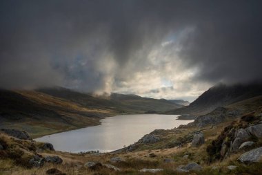 Sonbaharın erken saatlerinde Ogwen Vadisi boyunca Llyn Ogwen ve Tryfan 'ın karamsar gökyüzü altında fotokopi alanı ile manzara.