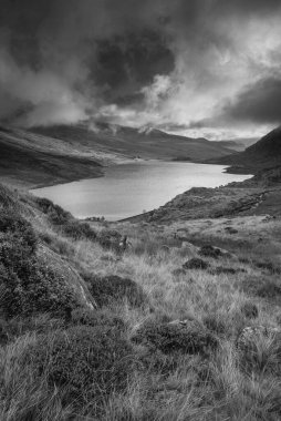 Ogwen Vadisi boyunca Llyn Ogwen ve Tryfan ile birlikte karanlık akşam gökyüzü altında fotokopi uzayıyla birlikte siyah ve beyaz sonbahar dönemi manzarası