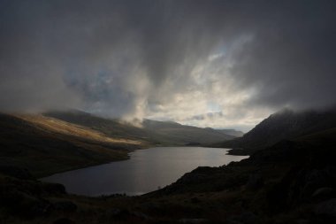 Sonbaharın erken saatlerinde Ogwen Vadisi boyunca Llyn Ogwen ve Tryfan 'ın karamsar gökyüzü altında fotokopi alanı ile manzara.