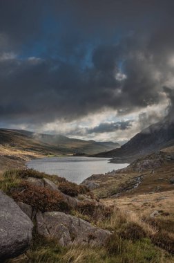 Sonbaharın erken saatlerinde Ogwen Vadisi boyunca Llyn Ogwen ve Tryfan 'ın karamsar gökyüzü altında fotokopi alanı ile manzara.