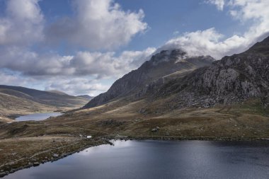 Uçan İHA 'nın hava görüntüsü Sonbaharın ilk dönemlerinde Epic Güz manzarası Ogwen vslley boyunca dramatik gökyüzü ve dağları ile Snowdonia Ulusal Parkı' nda