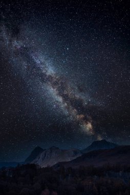 Samanyolu 'nun dijital kompozit görüntüsü ve Lake District' teki Holme Fell 'den bakan büyüleyici Langdale Pikes' in destansı manzarası.