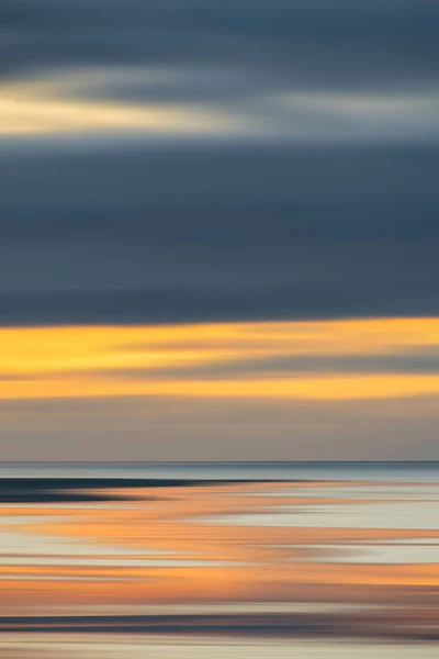 穏やかな海に反射するパステルカラーで遠くの山々の意図的なカメラの動き日没の風景のイメージ — ストック写真