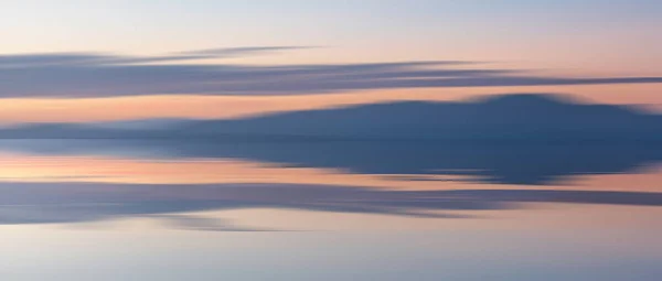 カンブリア州からスコットランドのダンフライとガロウェイの山々に向かって海を横切る壮大な夕日の風景画像穏やかな海に反映されたパステルカラー — ストック写真