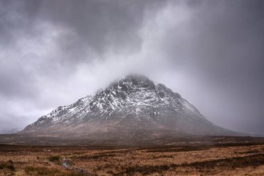 Stob Dearg Buachaille Etive Mor 'un kış manzarası. Rannoch Moor' dan karlı zirvesi ve güzel dramatik bulut oluşumlarıyla izleniyor.