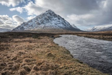 Önplanda Etive Nehri 'nin güzel kış manzarası. Arkaplanda ikonik kar örtülü Stob Dearg Buachaille Etive Mor dağı var.