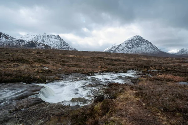 Önplanda Etive Nehri 'nin güzel kış manzarası. Arkaplanda ikonik kar örtülü Stob Dearg Buachaille Etive Mor dağı var.