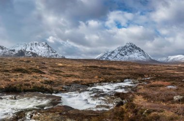 Önplanda Etive Nehri 'nin güzel kış manzarası. Arkaplanda ikonik kar örtülü Stob Dearg Buachaille Etive Mor dağı var.