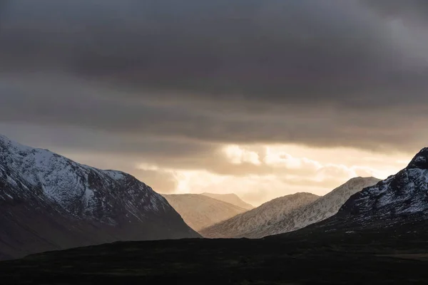 スコットランドの高地にあるEtive MorのLost Valleyの風景の上に見事な劇的な冬の夕日が輝いています — ストック写真