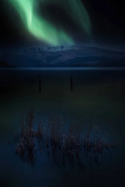 令人叹为观止的充满活力的北极光奥若拉合成图像覆盖了罗蒙德湖和苏格兰山脉的风景 — 图库照片