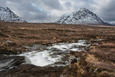 Önplanda Etive Nehri 'nin güzel kış manzarası. Arkaplanda ikonik kar örtülü Stob Dearg Buachaille Etive Mor dağı var.