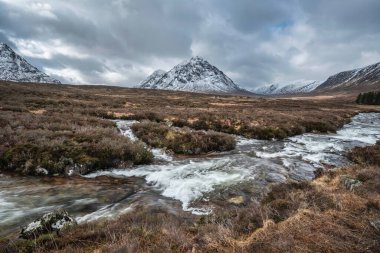 Önplanda Etive Nehri 'nin güzel kış manzarası. Arkaplanda ikonik kar örtülü Stob Dearg Buachaille Etive Mor dağı var.
