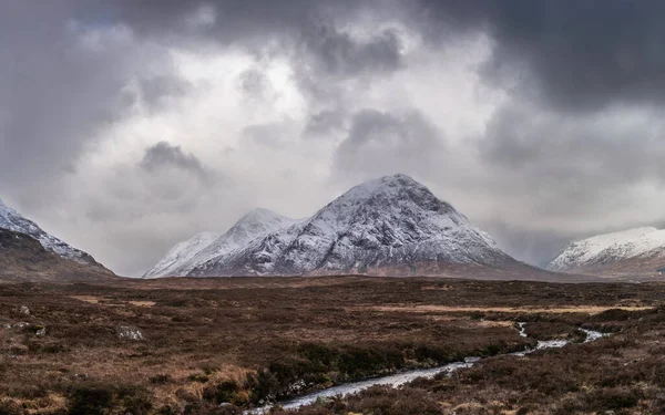 Stob Dearg Buachaille Etive Mor 'un kış manzarası. Rannoch Moor' dan karlı zirvesi ve güzel dramatik bulut oluşumlarıyla izleniyor.