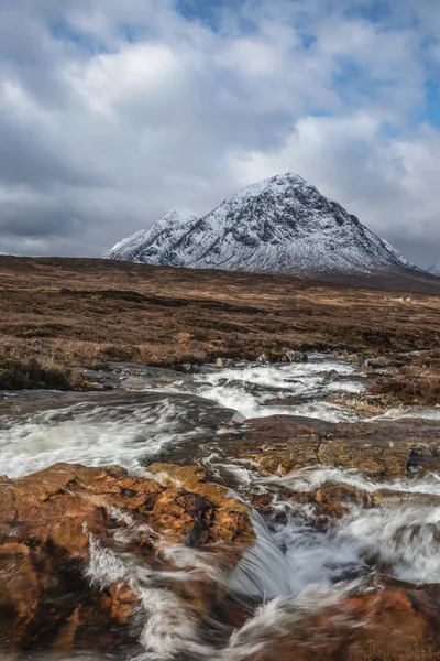 Önplanda Etive Nehri 'nin güzel kış manzarası. Arkaplanda ikonik kar örtülü Stob Dearg Buachaille Etive Mor dağı var.