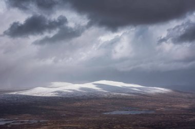 Kar fırtınası sırasında İskoçya 'nın dağlarının tepesinden Rannoch Moor' a kadar uzanan güzel kış manzarası ve yüksek rüzgarlarla dağların tepesinden kayma.