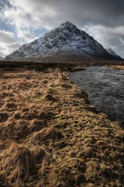 Önplanda Etive Nehri 'nin güzel kış manzarası. Arkaplanda ikonik kar örtülü Stob Dearg Buachaille Etive Mor dağı var.