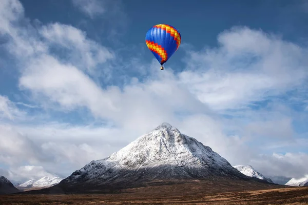 見事な象徴的な風景の上を飛ぶ熱気球のデジタル複合画像スコットランド高地のStob Dearg Buachaille Etive Mor山の冬のイメージ — ストック写真