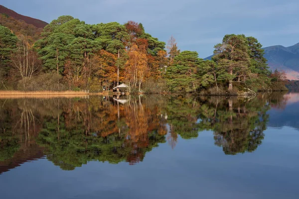 鮮やかな秋の日の出の間にダーウェントウォーターのボートハウスの壮大な風景のイメージ湖を囲む森林と — ストック写真