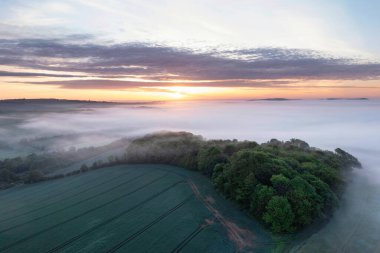 Güzelim insansız hava aracı görüntüsü. Sis denizi güney yamaçlarında ilerliyor. İngiliz kırsalında bahar gündoğumu boyunca.
