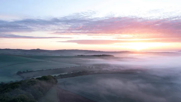 春の日の出の間に南ダウン英語の田舎を渡って圧延霧の海の美しいドローン風景のイメージ — ストック写真