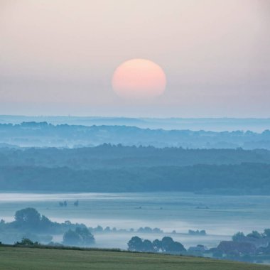 Güzel yaz gündoğumu manzarası uzaktan sisli ve sisli güneşli tarlalara bakıyor.