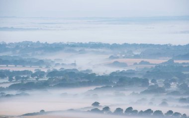 Stunning landscape image of layers of mist rolling over South Downs National Park English countryside during misty Summer sunrise