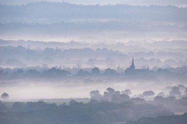 Stunning landscape image of layers of mist rolling over South Downs National Park English countryside during misty Summer sunrise