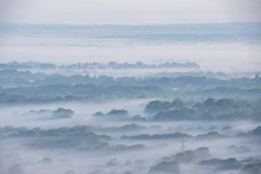 Sisli yaz gündoğumu sırasında South Downs Ulusal Parkı 'nın kırsalında süzülen sis tabakalarının çarpıcı manzarası.