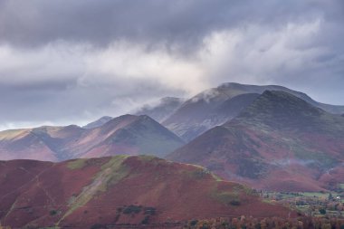 Göl Bölgesi 'ndeki Walla Crag' dan Derwentwater 'ın üzerinden Catbell' lere ve çarpıcı sonbahar renkleriyle uzak dağlara bakan destansı sonbahar manzarası.