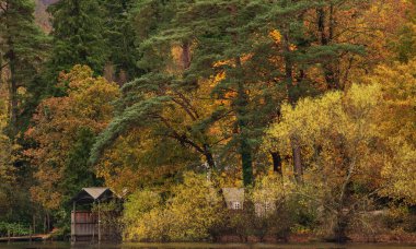 Göl Bölgesi Derwentwater 'daki kayıkhanenin destansı manzarası canlı sonbahar ormanlarıyla çevrili.