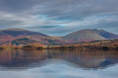 Distict Gölü 'ndeki Manesty Parkı' ndan Derwentwater yüzeyi boyunca ilerleyen güz güneşli Skiddaw Sıradağları 'na bakan destansı gündoğumu manzarası.