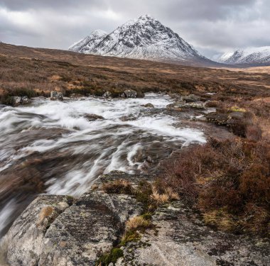 Önplanda Etive Nehri 'nin güzel kış manzarası. Arkaplanda ikonik kar örtülü Stob Dearg Buachaille Etive Mor dağı var.