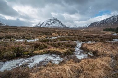 Önplanda Etive Nehri 'nin güzel kış manzarası. Arkaplanda ikonik kar örtülü Stob Dearg Buachaille Etive Mor dağı var.