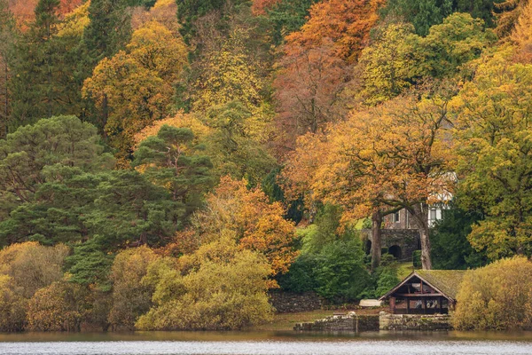 湖地区のダーウェントウォーターにあるボートハウスの壮大な風景画像活気に満ちた秋の色の森に囲まれて — ストック写真