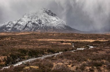 Stob Dearg Buachaille Etive Mor 'un kış manzarası. Rannoch Moor' dan karlı zirvesi ve güzel dramatik bulut oluşumlarıyla izleniyor.