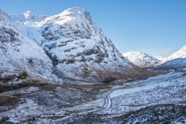 Güzel kış manzarası mavi gökyüzü Glencoe Rannoch Moor vadisi boyunca etrafı karla kaplı dağlarla